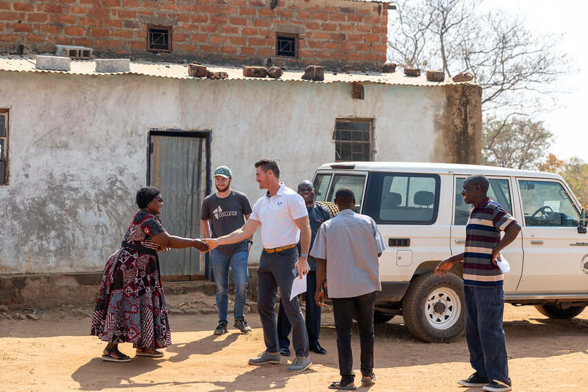 James Adair, IMB missionary, greets leaders in a village with Presley Adams, summer Nehemiah missionary. (Photo/IMB)