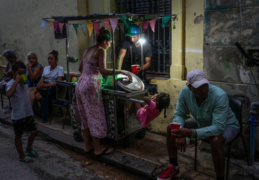 A woman buys soup from a street vendor during a power outage in Havana, Monday, Oct. 21, 2024. (AP Photo/Ramon Espinosa)