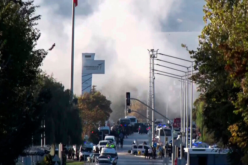 Smoke rises as emergency rescue teams and police officers respond outside Turkish Aerospace Industries Inc. on the outskirts of Ankara, Turkey, Wednesday, Oct. 23, 2024. (IHA via AP)