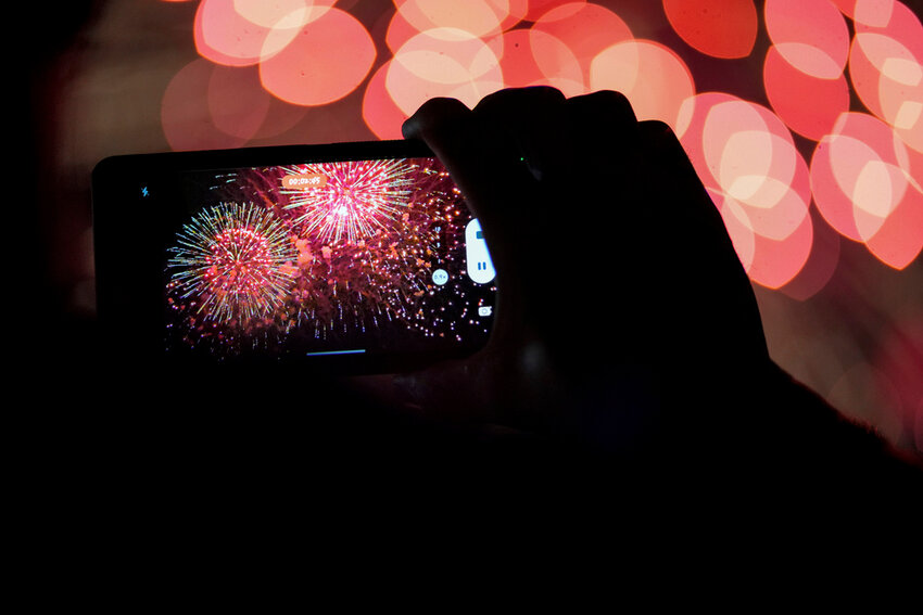 A spectator records a cell phone video as fireworks are launched over the Ohio River in Cincinnati on Sept. 3, 2023. (AP Photo/Aaron Doster)