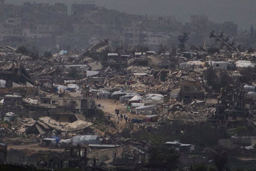 People walk among buildings destroyed during the Israeli air and ground offensive in the Gaza Strip, as seen from southern Israel, Thursday, March 20, 2025. (AP Photo/Leo Correa)