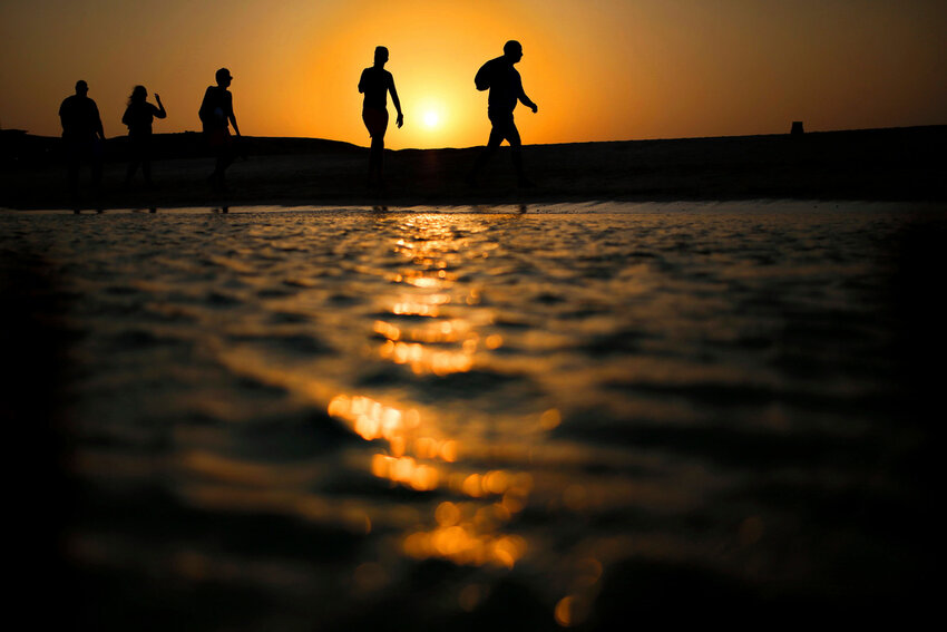 Tourists walk on the Giftun Island beach as the sun sets over the Red Sea in Hurghada, Egypt, Aug. 20, 2015. (AP Photo/Hassan Ammar, File)