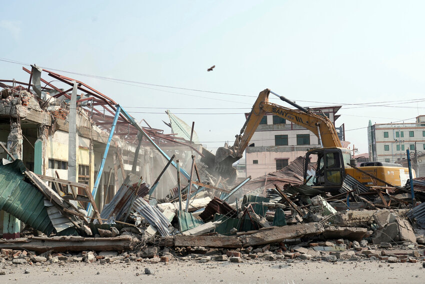 A volunteer drives a backhoe to clear debris at a market, one month after a strong earthquake in Naypyitaw, Myanmar, Monday, April 28, 2025. (AP Photo/Aung Shine Oo)