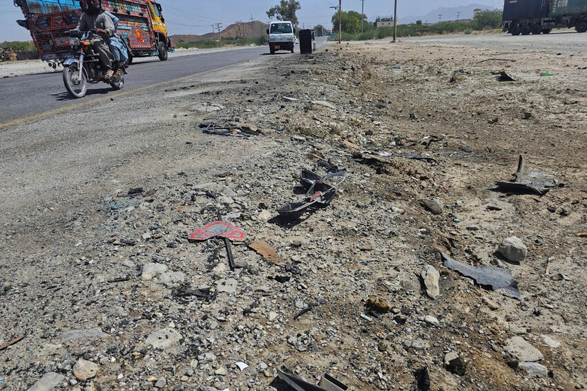A motorcyclist and vehicles drive past the site of a suicide bombing at a highway on the outskirts of the city of Khuzdar, in southwestern Pakistan, Wednesday, May 21, 2025. (AP Photo)