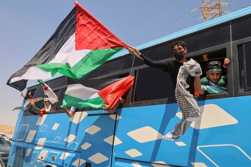 Members of a convoy of at least 1,500 people, including activists and supporters from Algeria and Tunisia, wave Palestinian flags from a bus as the group travels toward Gaza via Egypt's Rafah Crossing, in Zawiya, Libya, Tuesday, June 10, 2025. (AP Photo)