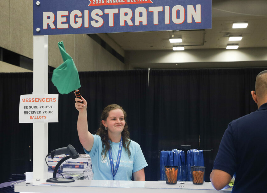 Chloe Taylor, a member of Lake Shore Baptist Church in Lake Dallas, Texas, waves a flag to call the next person in line at SBC registration in Dallas. (Baptist Press/Josselyn Guillen)