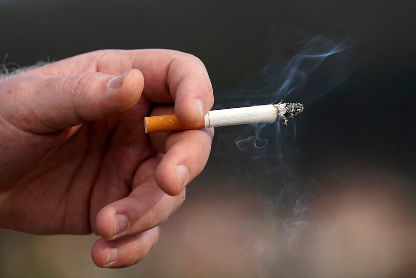 A man holds a lit cigarette while smoking in San Francisco, Dec. 2, 2020. (AP Photo/Jeff Chiu, File)
