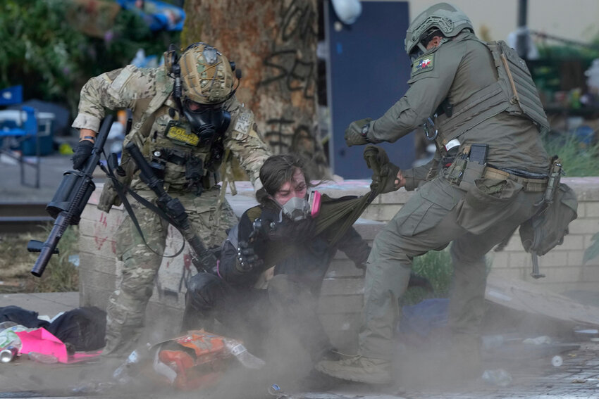 Law enforcement officers grab a demonstrator outside the U.S. Immigration and Customs building during a riot Saturday, June 14, 2025, in Portland, Ore. (AP Photo/Jenny Kane)