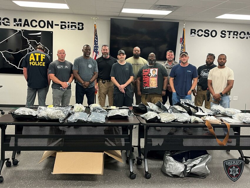 Law enforcement personnel pose behind confiscated drugs. (Photo/Bibb County Sheriff’s Office via Facebook)