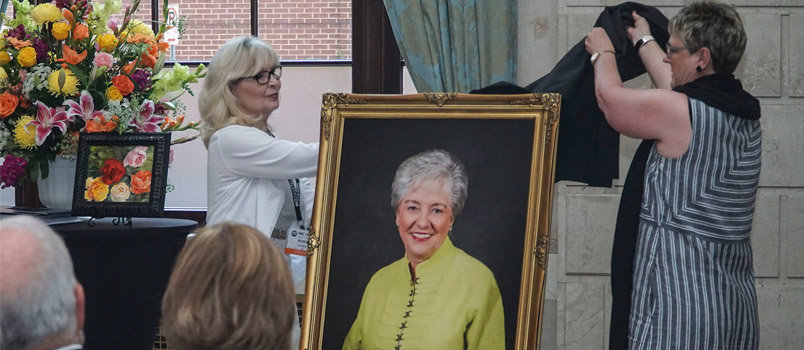 Carol Causey, left, director for the Woman's Missionary Union (WMU) missions resource center, and Andrea Mullins, right, retired publisher for New Hope Publishers, unveil a photo of retiring WMU executive director Wanda Lee at her retirement celebration prior to the WMU missions celebration and annual meeting Saturday, June 11, in St. Louis. JENNA WACHSMUTH