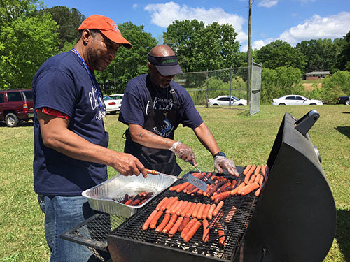 Cornerstone Baptist Church deacon Dwight Reese, left, and Powerhouse member Barrion Boyle, left, grill hot dogs.   JOE WESTBURY/Index