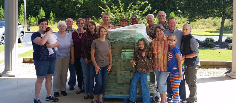 Some of the members of Foothills Community Church in Marble Hill gather around one of several pallets they shipped to storm-ravaged Houston.  FOOTHILLS CHURCH/Special