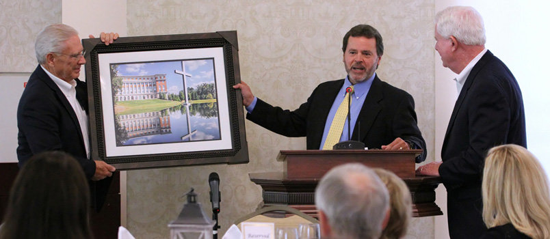 Assistant Executive Director Bobby Boswell, left, presides in a presentation of a photo of the Missions Center building last fall to retiring Executive Director J. Robert White, right. University of North Georgia Campus Minister Ken Jones, center participates in the event which was part of a staff appreciation banquet for White. Boswell announced his retirement this morning.  BRYAN NOWAK/Special