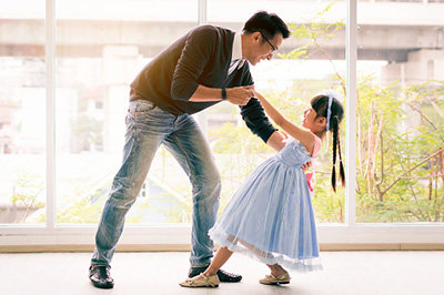 Cute little girl is dancing with her daddy. Having fun at home together concept