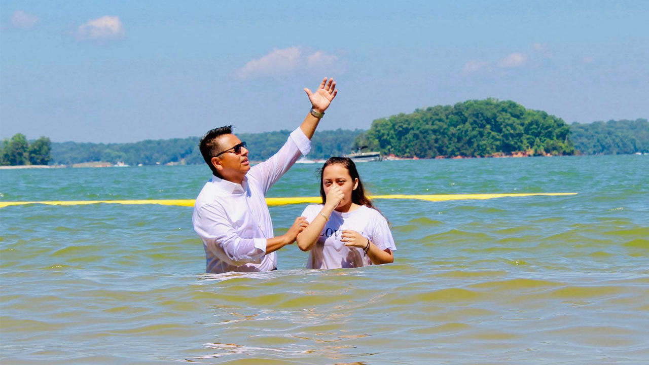 Javier Chavez, pastor of Amistad Cristiana in Gainesville, baptizes a young girl in May of this year in Lake Lanier near Flowery Branch. The joint baptism service with two other churches was so heavily attended that more than 80 people were unable to witness it for lack of parking. AMISTAD CRISTIANA/Special