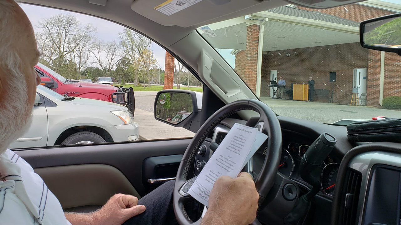 Chris Hurst holds his church bulletin while listening to Pastor Mark Spraggins at Friendship Baptist Church in Lee County on Sunday, March 22. Friendship held a drive-in worship service, with attendees bringing their tithe through their car window. FRIENDSHIP BC/Special