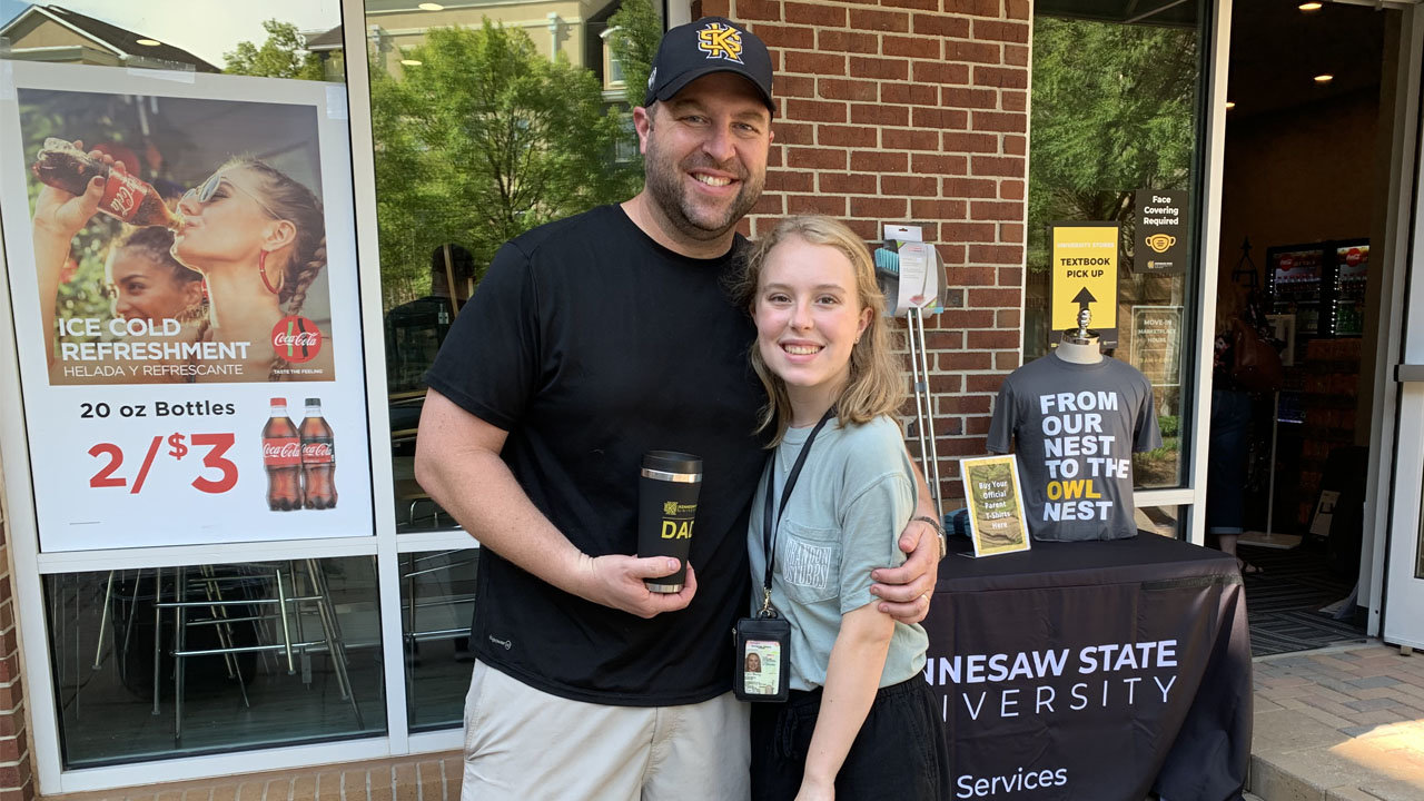 Index editor Scott Barkley holds his just-bought "KSU Dad" coffee tumbler beside his daughter, Rylee, at Kennesaw State University.
