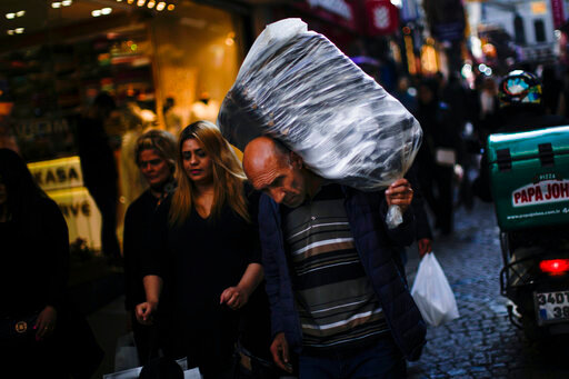 A man carries goods on his back in a commercial area in Istanbul, Turkey, Tuesday, Nov. 2, 2021. Many Turkish consumers are faced with increased hardship as prices of food and other goods have soared in recent years. The yearly consumer price index increased by 19.9% in October, up from 19.58% in September, according to official data by the Turkish Statistical Institute released on Nov. 3. (AP Photo/Francisco Seco)
