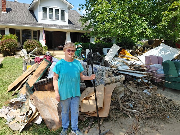 Barbara Dillon, who attends First Baptist Church in Waverly and lives across the street from the church, stands beside a pile of her belongings that were removed from her flooded home. (Photo/Lonnie Wilkey)