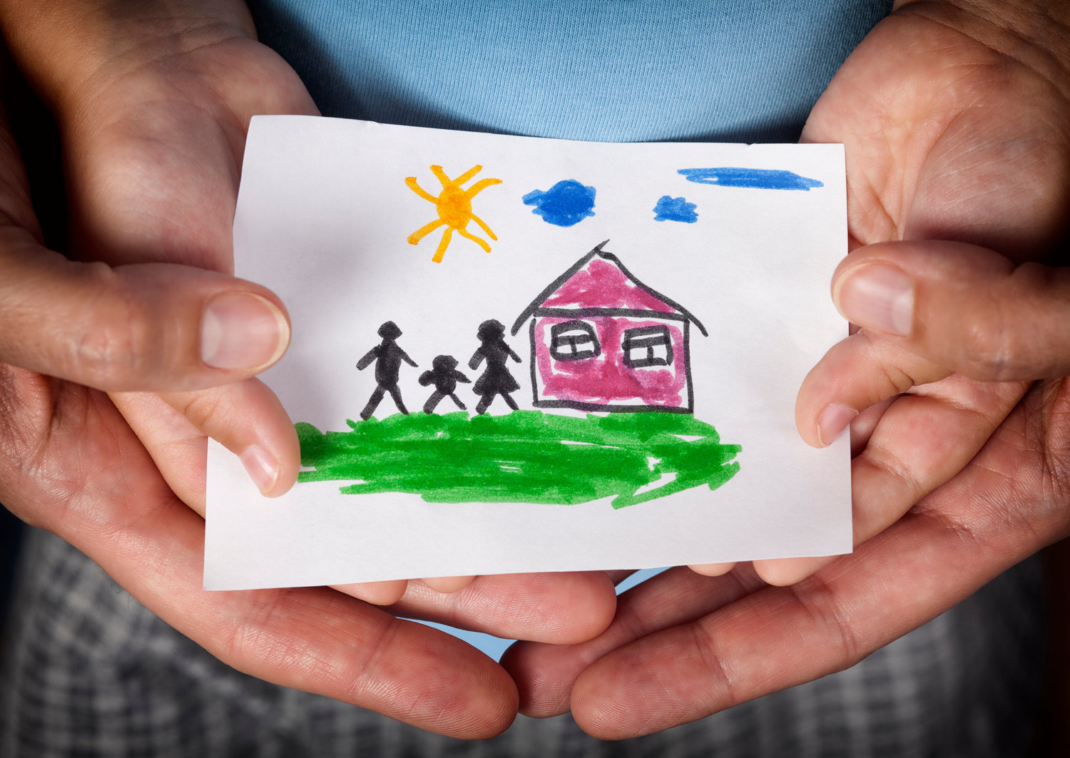 Child and his mom holding a drawn house with family.
