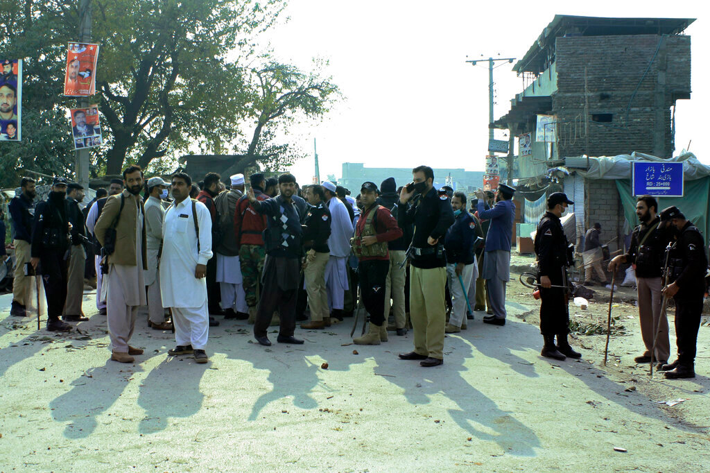 Police officers control an angry crowd protesting against a mentally unstable man accused of blasphemy, in Mandani, an area of Charsadda district, Pakistan, Monday, Nov. 29, 2021. A Muslim mob burned a police station and four police posts overnight in northwest Pakistan after officers refused to hand over a mentally unstable man accused of desecrating Islam's holy book, the Quran, authorities said Monday. (AP Photo/Zia Mohammad)