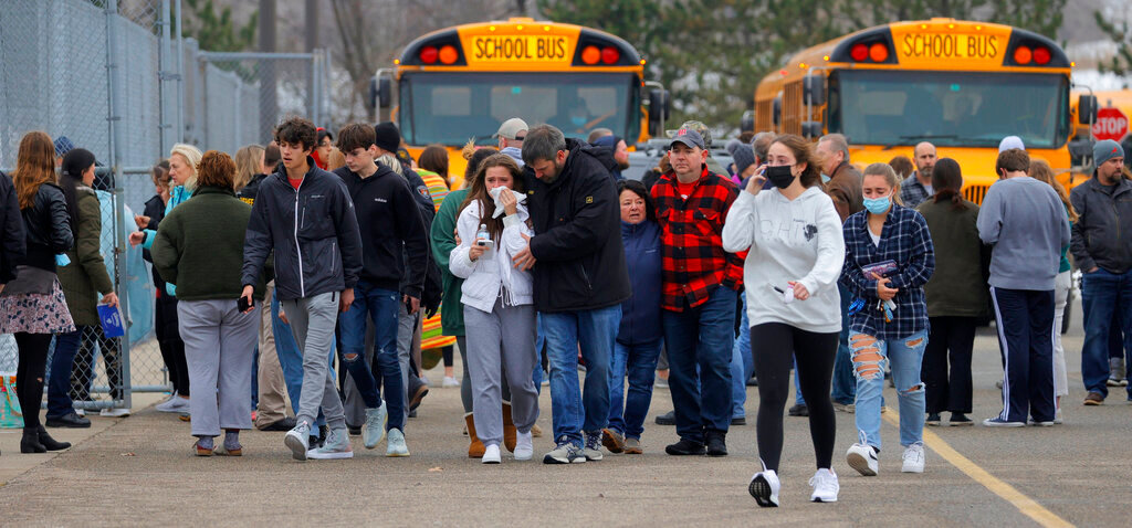 Parents walk away with their kids from the Meijer's parking lot in Oxford where many students gathered following an active shooter situation at Oxford High School in Oxford on November 30, 2021. Police took a suspected shooter into custody and there were multiple victims, the Oakland County Sheriff's office said. County Sheriff's office said, but no fatalities.