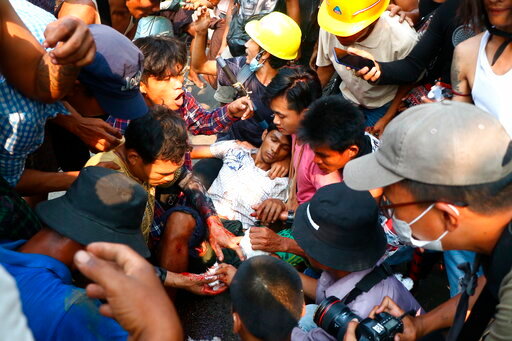 FILE - Anti-coup protesters surround an injured man in Hlaing Thar Yar township in Yangon, Myanmar Sunday, March 14, 2021. The killing of at least 65 protesters in Myanmar’s biggest city on March 14 this year was planned and premeditated, and the perpetrators must be brought to justice, a rights watchdog said in a report released Thursday, Dec. 2, 2021. (AP Photo/File)