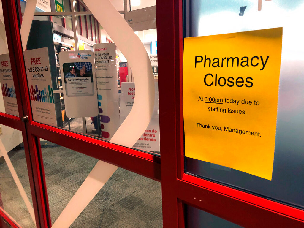 A sign is posted outside a CVS pharmacy on Thursday, Dec. 2, 2021 in Indianapolis. A rush of vaccine-seeking customers and staff shortages are squeezing drugstores around the country. That has led to frazzled workers and even temporary pharmacy closures.    (AP Photo/Tom Murphy)