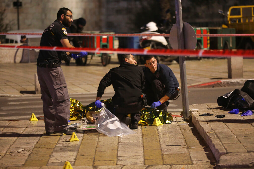 Israeli police examine the body of a man shot near Damascus Gate to the Old City of Jerusalem, Saturday, Dec. 4, 2021. Israeli police shot a Palestinian on Saturday after an ultra-Orthodox Jewish man was stabbed and wounded near Damascus Gate in Jerusalem's Old City, a crowded area that is often the scene of demonstrations and clashes.(AP Photo/Mahmoud Illean)