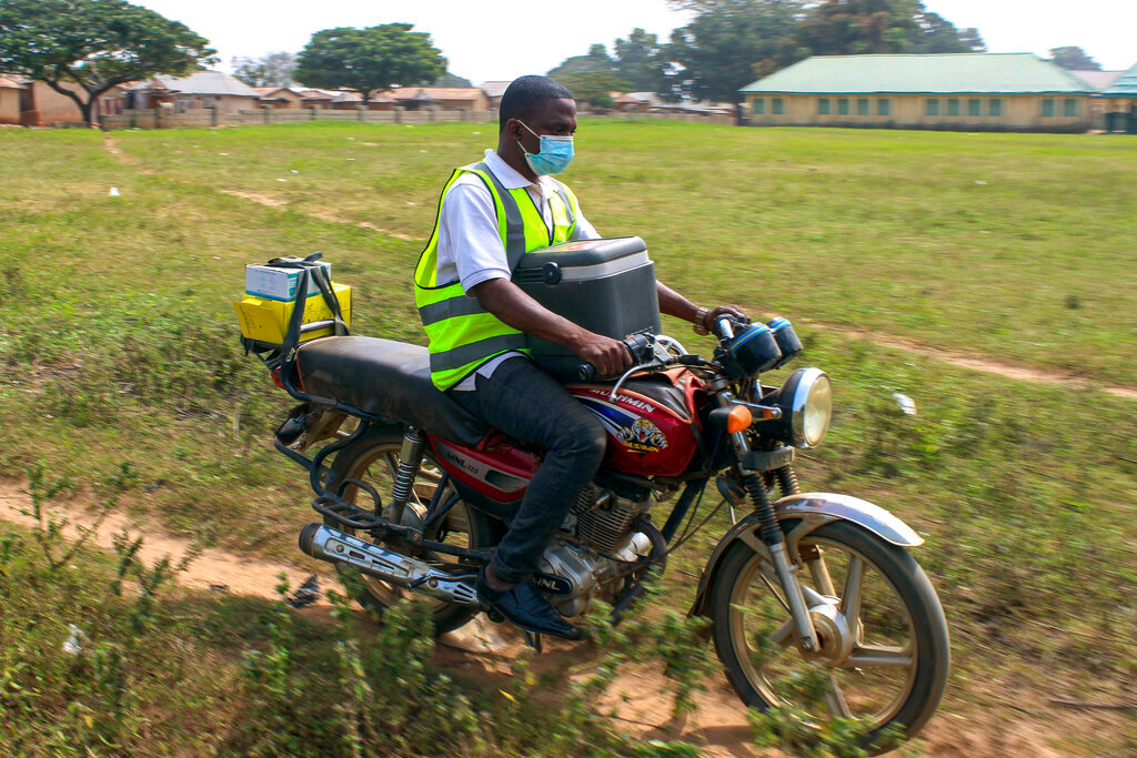 Yunusa Bawa, a community health worker, ride on a motorbike with a box  of AstraZeneca coronavirus vaccine, at Sabon Kuje outskirts of Abuja, Nigeria, Monday, Dec 6, 2021. As Nigeria tries to meet an ambitious goal of fully vaccinating 55 million of its 206 million people in the next two months, health care workers in some parts of the country risk their lives to reach the rural population. (AP Photo/Gbemiga Olamikan)