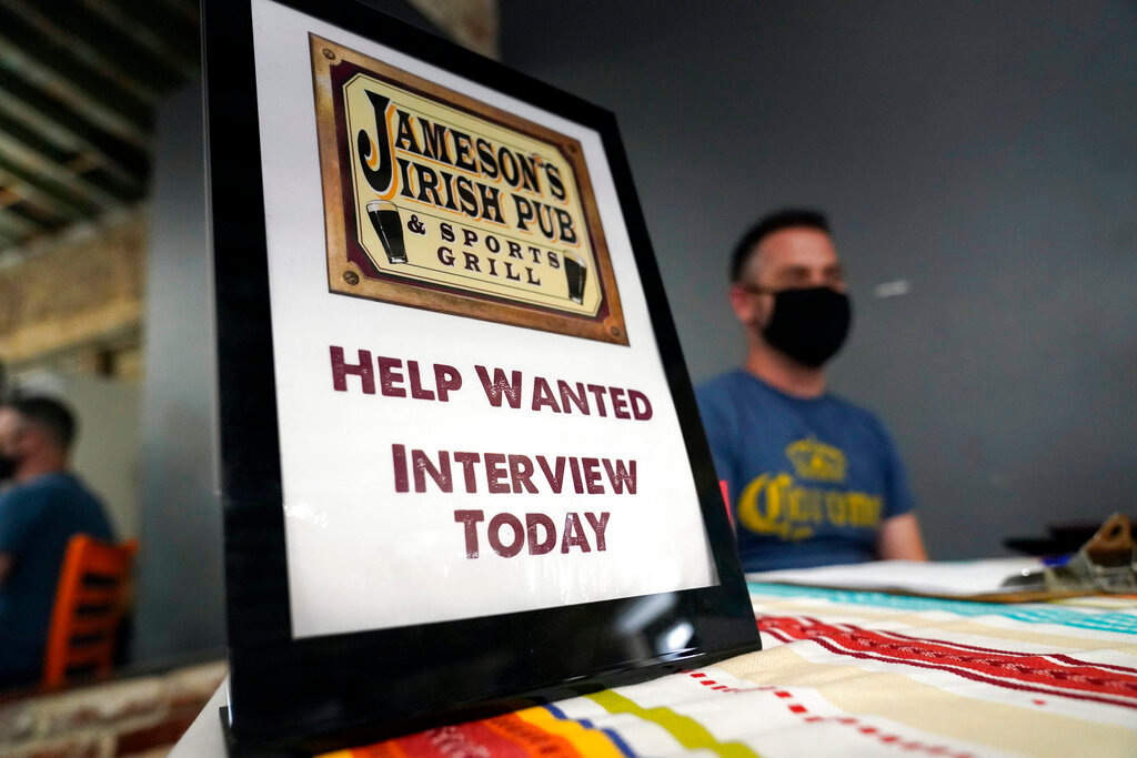 A hiring sign is shown at a booth for Jameson's Irish Pub during a job fair on Sept. 22, 2021, in the West Hollywood section of Los Angeles. Hiring in California slowed significantly in November 2021 even as the state's unemployment rate dipped below 7% for the first time since March 2020, at the start of the pandemic, according to data made public Friday, Dec. 17, 2021. (AP Photo/Marcio Jose Sanchez, File)