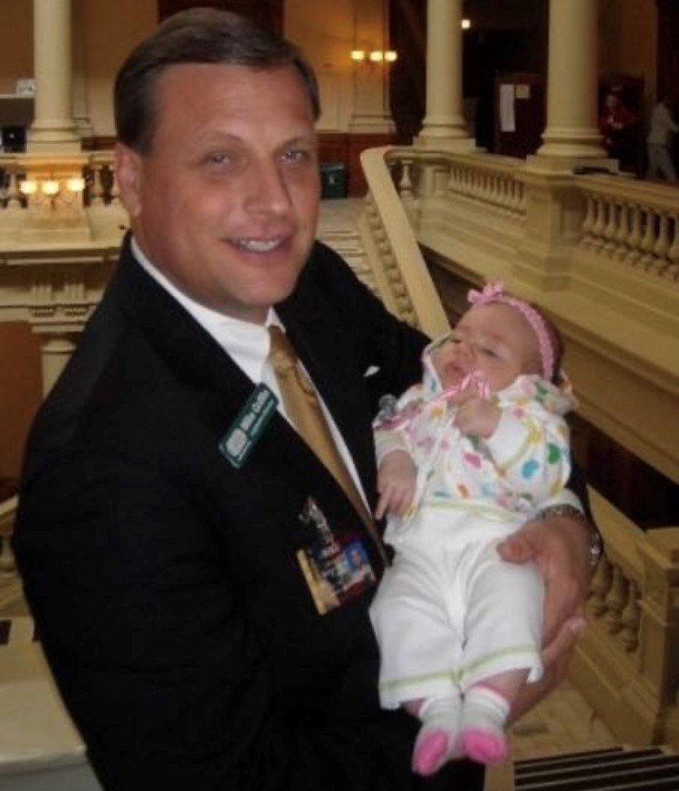 Mike Griffin holds his first grandchild, Adah Grace Johnson, in the state Capitol.