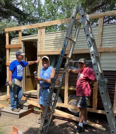 A three-man crew build a facade on a 1950s camper to blend with campus cabins. (Photo/Lilly Mucklow)