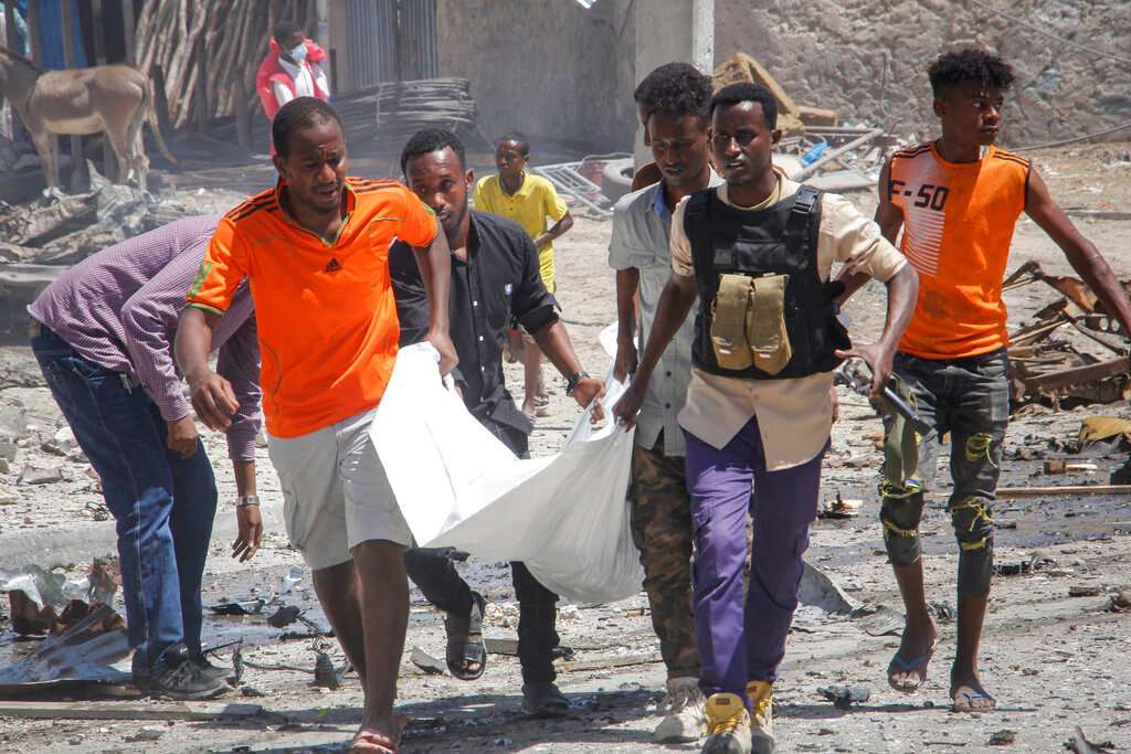 Rescuers carry away the body of a civilian who was killed in a blast in Mogadishu, Somalia, Wednesday, Jan. 12, 2022. A large explosion was reported outside the international airport in Somalia's capital on Wednesday and an emergency responder said there were deaths and injuries. (AP Photo/Farah Abdi Warsameh)
