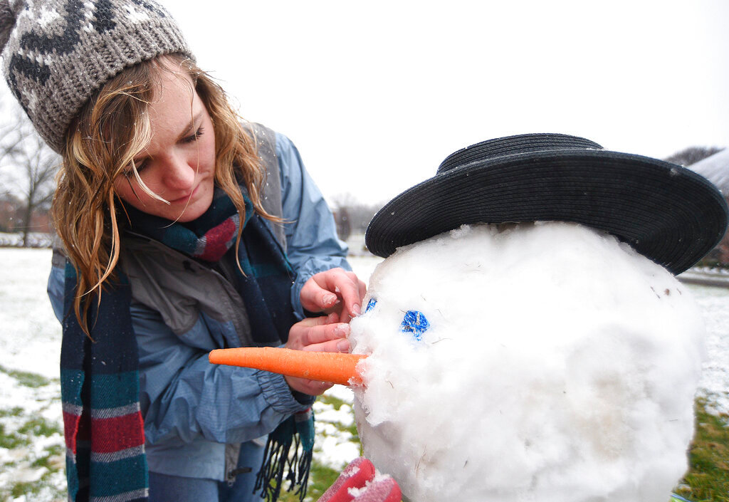 Staff Photo by Matt Hamilton / Lee University student Kealey White adds eyes and a nose to the snowman she made with her roommates as the snow falls at Lee University on Sunday, January 16, 2022.