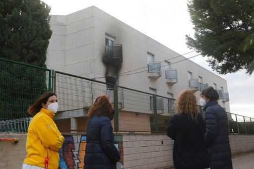 People look towards a nursing home after a fire in the municipality of Moncada just north of Valencia, Spain, Wednesday Jan. 19, 2022. Spanish authorities say that at least five people have died in a fire at a nursing home near Valencia in eastern Spain. Emergency services for the Valencia region said Wednesday that in addition to the victims another 11 people required hospital treatment. (Alberto Saiz)