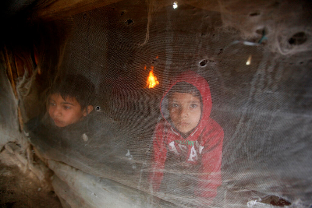 Displaced Syrian boys look through their tent window, as they try to stay warm at a refugee camp near the southern port city of Zahrani, Lebanon, Wednesday, Jan. 19, 2022. A snowstorm in the Middle East has left many Lebanese and Syrians scrambling to find ways to survive. Some are burning old clothes, plastic and other hazardous materials to keep warm as temperatures plummet and poverty soars. (AP Photo/Mohammed Zaatari)