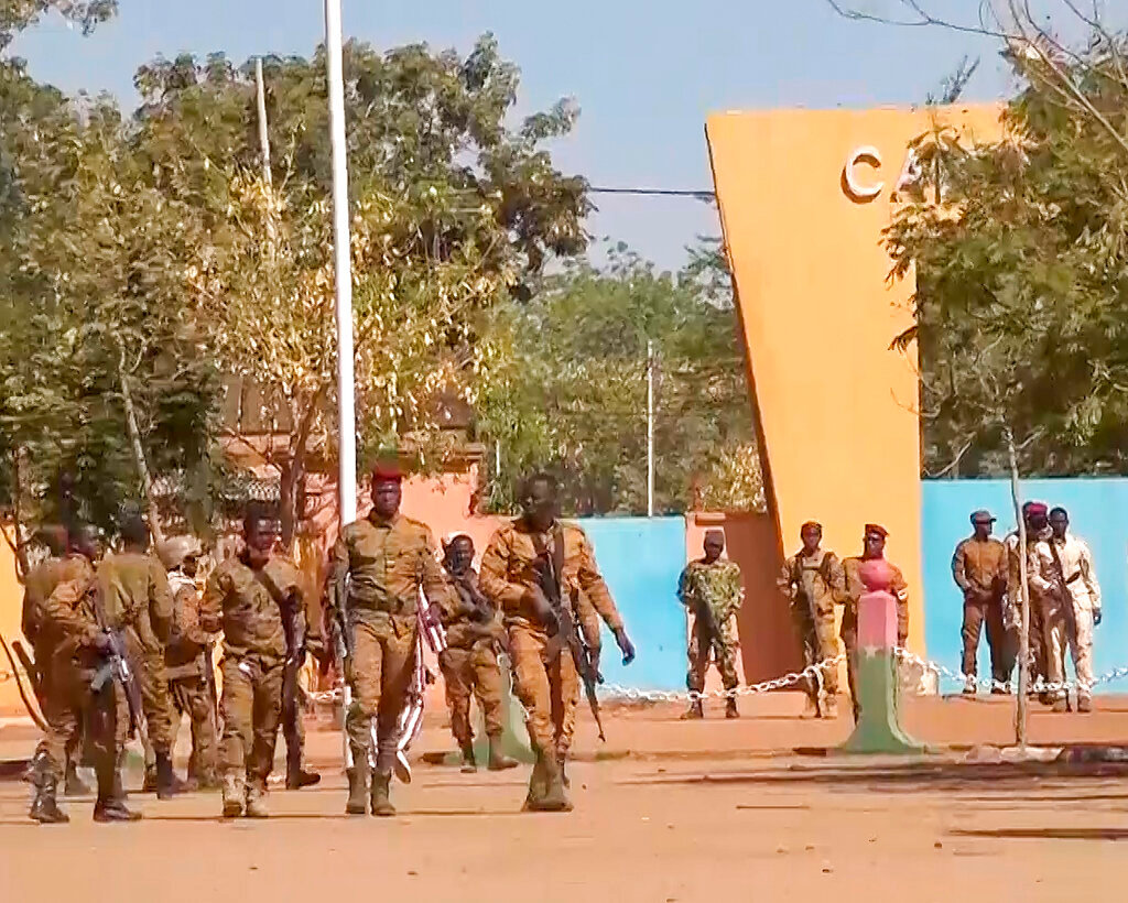 In this image made from video, Burkina Faso mutinous soldiers walk outside the Guillaume Ouedraogo military camp in Ouagadougou, Monday Jan. 24, 2022. Mutinous soldiers said they detained Burkina Faso's President Roch Marc Christian Kabore on Monday, a day after rebellious troops seized a military barracks, setting off a series of gunbattles in the capital of the West African country. (AP Photo)