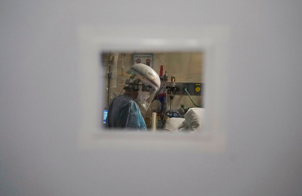 A nurse tending to a COVID-19 patient, is seen through a small window in an intensive care unit ,at Mission Hospital in Mission Viejo, Calif., on Dec. 21, 2020. Many American hospitals are looking broad for health care workers, saying they're facing a dire shortage of nurses amid the slogging pandemic. It could be just in time as there's an unusually high number of green cards available this year for foreign professionals seeking to move to the United States. (AP Photo/Jae C. Hong, File)