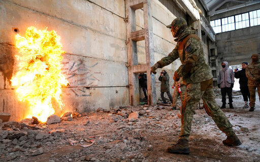 A local resident throws a Molotov cocktail against a wall during an all-Ukrainian training campaign "Don't panic! Get ready!" close to Kyiv, Ukraine, Sunday, Feb. 6, 2022. Russia has denied any plans of attacking Ukraine, but urged the U.S. and its allies to provide a binding pledge that they won't accept Ukraine into NATO, won't deploy offensive weapons, and will roll back NATO deployments to Eastern Europe. Washington and NATO have rejected the demands. (AP Photo/Efrem Lukatsky)