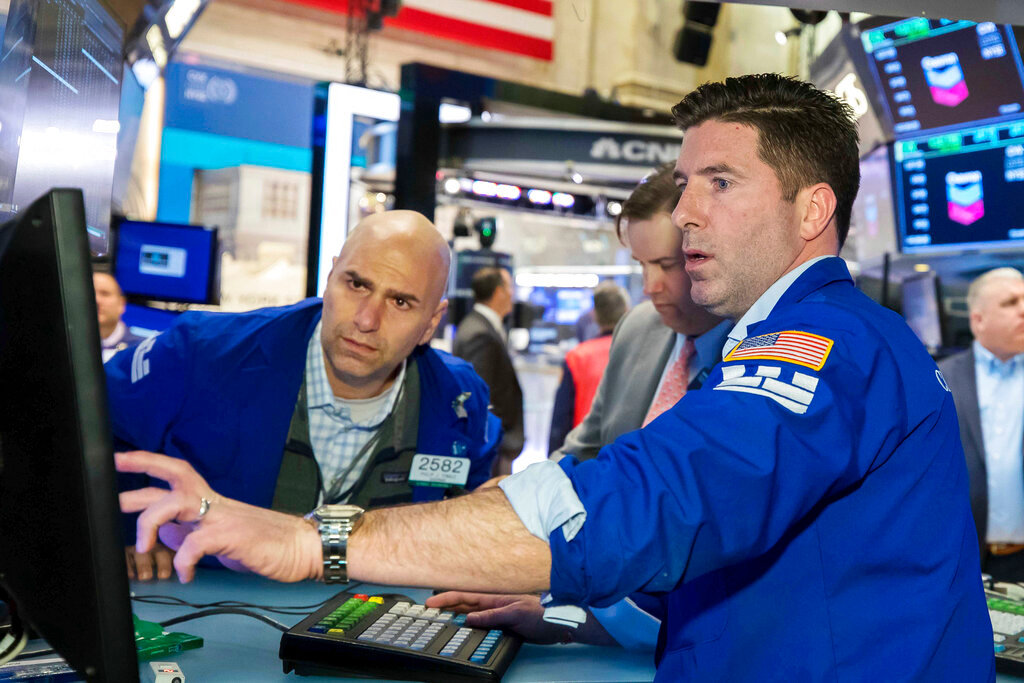 In this photo provided by the New York Stock Exchange, specialist Thomas McArdle, right, works at his post on the trading floor, Tuesday, March 1, 2022. Stocks fell following a volatile day for major indexes as investors tried to measure how the conflict will impact the global economy. (Courtney Crow/New York Stock Exchange via AP)