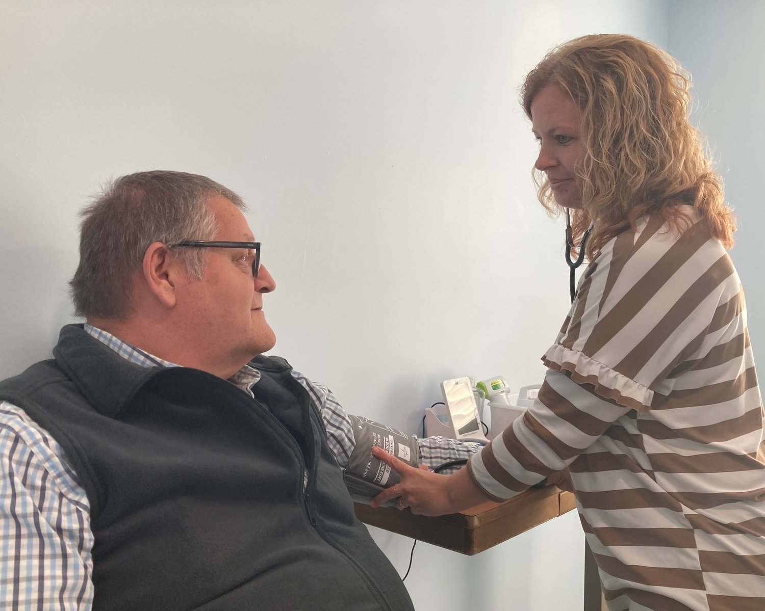 Wendy West, director of Good Health Ministries, tries her blood pressure cup on Associational Missionary Freddy Gardner. (Index/Roger Alford)