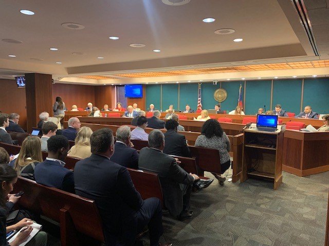 A group watches as a legislative committee discusses a gambling bill.