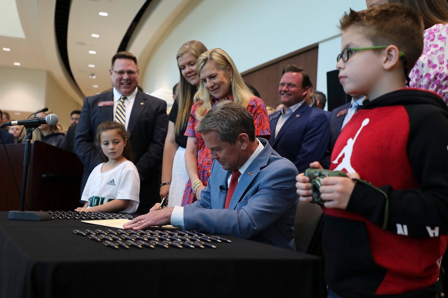 Georgia Gov. Brian Kemp signs HB1084 on April 28, 2022, in Forsyth County, Ga., as his wife Marty and daughter Lucy look on. Rep. Josh Bonner, who sponsored the bill, is at left. (Photo/Governor's Office)