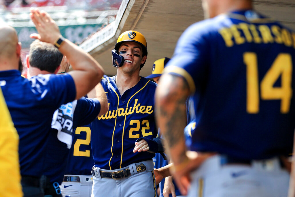 Milwaukee Brewers' Christian Yelich high-fives teammates in the dugout after scoring a run during the ninth inning against the Cincinnati Reds in Cincinnati, Wednesday, May 11, 2022. The Reds won 14-11. (AP Photo/Aaron Doster)