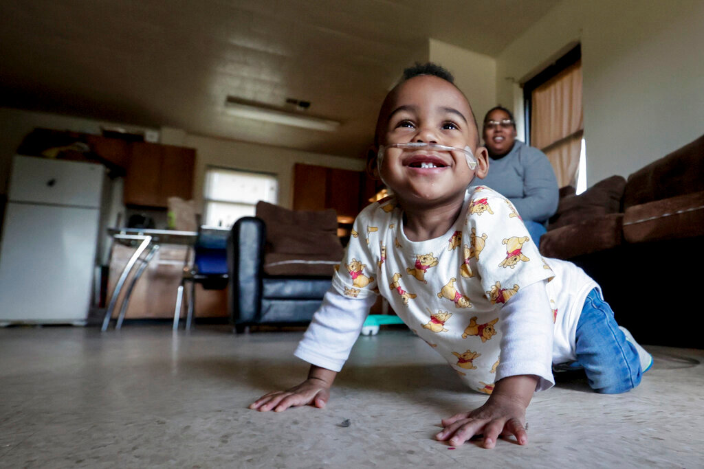 Curtis Means crawls around as his mother, Michelle Butler, keeps an eye on him at their home in Eutaw, Ala., on Wednesday, March 23, 2022. (AP Photo/Butch Dill)