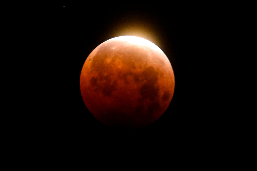 A total lunar eclipse is seen over Santa Monica Beach in Santa Monica, Calif., May 26, 2021. A total lunar eclipse will grace the night skies this weekend, providing longer than usual thrills for stargazers across North and South America. (AP Photo/Ringo H.W. Chiu)