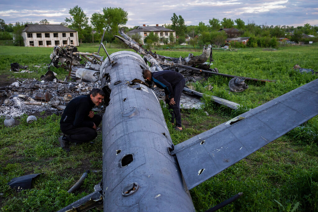 Oleksiy Polyakov, right, and Roman Voitko check the remains of a destroyed Russian helicopter in a field in the village of Malaya Rohan, Kharkiv region, Ukraine, Monday, May 16, 2022. (AP Photo/Bernat Armangue)
