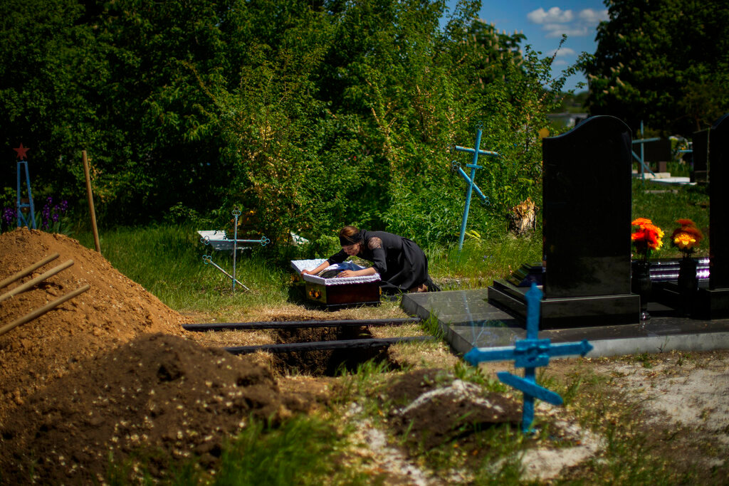 Iuliia Loseva cries over the coffin of her husband Volodymyr Losev during his funeral at a cemetery in Zorya Truda, Odesa region, Ukraine, Monday, May 16, 2022. Losev, a Ukrainian volunteer soldier, was killed on May 7 when the military vehicle he was driving ran over a mine in eastern Ukraine. (AP Photo/Francisco Seco)