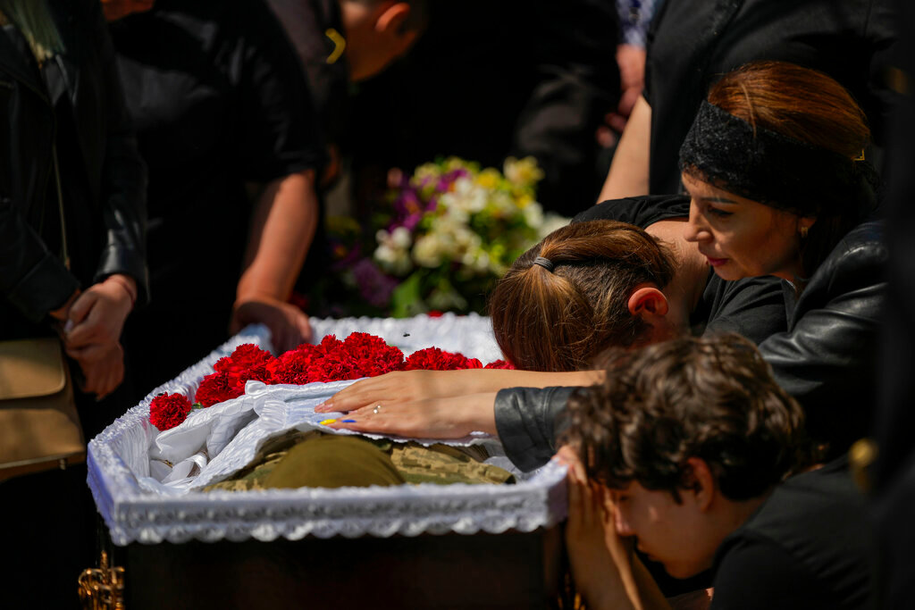 Iuliia Loseva, right, and her sons Hryhorii and Denys cry over the coffin of their husband and father Volodymyr Losev, during his funeral in Zorya Truda, Odesa region, Ukraine, Monday, May 16, 2022. Losev, a Ukrainian volunteer soldier, was killed May 7 when the military vehicle he was driving ran over a mine in eastern Ukraine. (AP Photo/Francisco Seco)